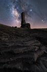 Dal basso turista irriconoscibile esplorare castello medievale in rovina sotto il cielo stellato con Via Lattea di notte — Foto stock