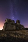 Desde abajo pintoresco paisaje de restos abandonados del antiguo castillo bajo la Vía Láctea - foto de stock