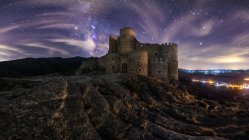 Дивовижні пейзажі покинутого стародавнього палацу на горі під барвистим зоряним небом вночі — стокове фото
