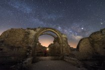 Vista trasera de los restos de turismo de viajeros sin rostro del antiguo castillo bajo la Vía Láctea en la noche estrellada - foto de stock