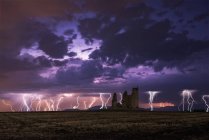 Amazing scenery of lightning storm on colorful cloudy sky over ruined old castle at night — Stock Photo