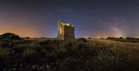 Da sotto paesaggio pittoresco di castello rovinato antico su prato sotto Via Lattea su cielo stellato di notte — Foto stock