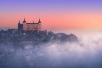 From above wonderful landscape of medieval castle built over city in misty colorful sunrise — Stock Photo