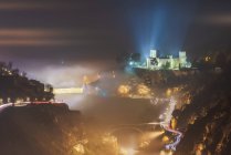 Von oben bezaubernde Szenerie mit leuchtender alter Burg und Brücke im nebligen Gebirge bei Sonnenaufgang — Stockfoto