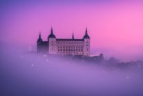 Сверху удивительный пейзаж средневекового замка, построенного над городом в туманном красочном восходе солнца — стоковое фото