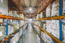 From above of empty narrow passage between big metal shelves with different packages and boxes in warehouse — Stock Photo