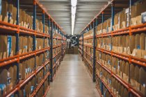From above of empty narrow passage between big metal shelves with different packages and boxes in warehouse — Stock Photo