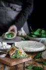 Dall'alto di gustosa tortilla con purea di spinaci freschi su tagliere in legno con signora senza volto che cucina su sfondo sfocato — Foto stock