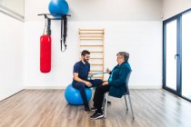 Elderly woman practicing resistance exercises with trainer in gym — Stock Photo