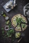 Von oben Ansicht der Pizza mit grünen Scheiben von Kürbis auf dem Tisch mit Gewürzen Olivenöl-Käse für vegetarisches Abendessen — Stockfoto
