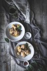 Vista dall'alto di cosce di pollo stufate con brodo in ciotola di ceramica bianca decorata con verde sul tavolo con spezie e bevande — Foto stock
