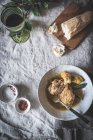 Vista superior de baquetas de frango cozido com caldo em tigela de cerâmica branca decorada com vegetação na mesa com pães de especiarias e bebidas — Fotografia de Stock