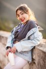 Gioiosa giovane donna in abito casual alla moda sorridente e guardando la fotocamera nella giornata di sole — Foto stock