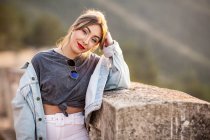 Fröhliche junge Frau im trendigen lässigen Outfit lächelt an sonnigen Tagen in die Kamera — Stockfoto