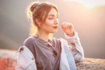 Радісна молода жінка в модному повсякденному вбранні посміхається і дивиться в сонячний день — стокове фото