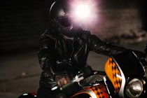 Элегантный мужчина сидит на своем красивом мотоцикле в гараже — стоковое фото