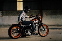 Элегантный мужчина сидит на своем красивом мотоцикле в гараже — стоковое фото