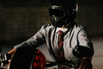 Homme élégant assis sur sa jolie moto à l'intérieur d'un garage — Photo de stock