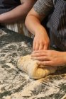 Von oben von gesichtslosen Frauenhänden, die am Tisch in der Bäckerei frische Teiglinge kneten — Stockfoto