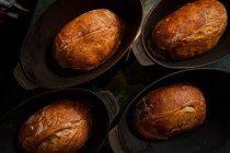 Top view of cooked golden bread loaves in cast iron forms on table — Stock Photo