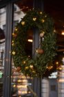 Fachada de cafetería con coloridas decoraciones de ramas de coníferas y árbol de Navidad con guirnaldas a la luz del día - foto de stock