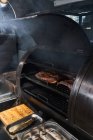 Dall'alto di fette affumicanti di carne su rastrelliera di griglia in barbecue — Foto stock