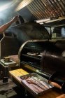 De dessus de chef de culture dans des gants griller morceaux de viande dans sur rack dans le barbecue — Photo de stock