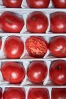 Вид зверху на соковиті стиглі червоні помідори, розташовані в коробці для продажу на ринку — стокове фото