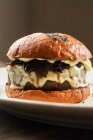 Délicieux hamburger de bœuf grillé maison avec fromage fondu servi sur une assiette sur la table — Photo de stock