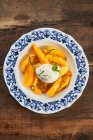 From above delicious bright prepared pieces of pumpkin with poached egg decorated with greens on plate on rustic wooden table — Stock Photo