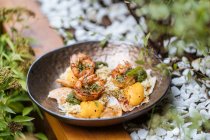 D'en haut savoureux oeufs frits frais avec des crevettes couvertes d'herbes dans une casserole sur une table en bois dans le jardin — Photo de stock