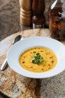 Зверху смачний апетитний овочевий вершковий суп у білій тарілці, що подається з вином у склянці за столом у кафе — стокове фото