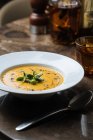De cima saborosa sopa de creme vegetal apetitosa em prato branco servido com vinho em vidro à mesa no café — Fotografia de Stock