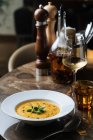 Von oben leckere Gemüsecremesuppe in weißem Teller serviert mit Wein im Glas am Tisch im Café — Stockfoto