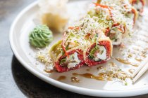 Sushi saboroso fresco com verdes na chapa branca na mesa — Fotografia de Stock
