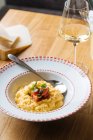 From above appetizing risotto with pumpkin decorated with sliced tomatoes and green in ornamental plate on table — Stock Photo