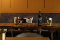 Dunkle Flasche auf gelbem Boden umgeben von Stühlen im eleganten Interieur eines stilvollen Restaurants mit warmem Licht der Mode runde Lampe — Stockfoto