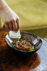 Gemüseköchin gießt appetitliche Sauce in Salat mit Lachs und Gemüse in Glasplatte auf dem Tisch — Stockfoto
