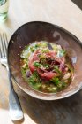 Salade de saumon fraîche savoureuse dans une sauce avec des légumes verts sur un bol sur la table — Photo de stock