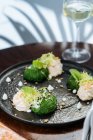 Dall'alto germogli di Bruxelles appetitosi saporiti con salsa alla panna ed erbe su piatto nero in ristorante — Foto stock
