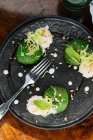 Сверху аппетитная брюссельская капуста со сливочным соусом и травами на черной тарелке в ресторане — стоковое фото