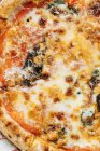 Сверху сочная запечённая пицца подается с сыром и травами на столе в ресторане — стоковое фото