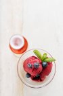 De cima de colheres roxas de sorvete em tigela de vidro decorado com mirtilo fresco e hortelã e servido com copo de bebida vermelha no restaurante — Fotografia de Stock
