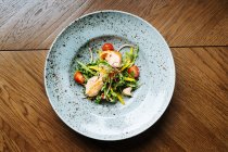 Visão superior de salada de vitamina com partes de pepino de tomates de cereja e filete de frango na chapa elegante no restaurante — Fotografia de Stock
