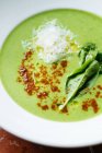 De cima da sopa de creme de brócolis em boliche branco com folhas de manjericão fresco e temperos em restaurante — Fotografia de Stock