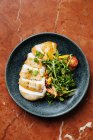 Vista dall'alto del filetto di pollo tagliato sul piatto con insalata fresca di pomodorini ed erbe aromatiche nel ristorante — Foto stock