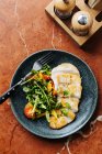 Draufsicht auf geschnittenes Hühnerfilet auf Teller mit frischem Salat aus Kirschtomaten und Kräutern im Restaurant — Stockfoto