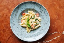 Vista superior do prato elegante com deliciosos pedaços de massa de tomate cereja e vegetação no restaurante — Fotografia de Stock