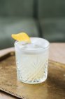 Зверху алкогольний коктейль з піною в стильному склі, прикрашений лимонною цедрою на столі акуратні сонцезахисні окуляри в ресторані — стокове фото
