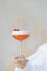 Cameriere anonimo in camicia bianca con delizioso cocktail rosso in elegante vetro decorato con lampone fresco — Foto stock